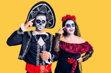 Arka planda Meksika kostümlü genç çift gülümsüyor. Tek parmağıyla işaret ediyor. Harika bir fikir ya da düşünce, iyi bir hafıza. 