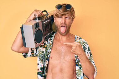 Yaz tarzı giyinmiş genç bir adam elinde teyp, dilini çıkarıp komik bir ifade takınıyor.. 