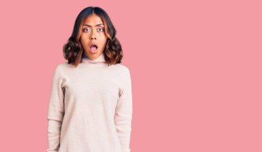 Balıkçı yaka kazak giyen genç, güzel, melez bir kadın şaşkınlık ve şaşkınlık dolu bir ifade, korku ve heyecanlı bir yüz ifadesiyle korku içinde.. 