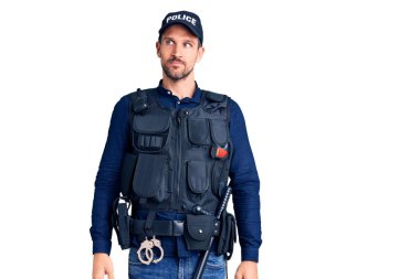 Polis üniforması giyen genç yakışıklı adam gülümsüyor, yan tarafa bakıyor ve düşünüyor.. 
