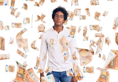 Afro saçlı, sıradan giyinmiş ve gözlüklü, yüzünde ciddi bir ifadeyle rahatlamış yakışıklı Afro-Amerikan bir adam. Basit ve doğal bir şekilde kameraya bakıyorsun..