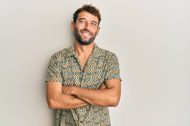 Sıradan moda tişörtü giyen, kollarını kavuşturup kameraya bakan yakışıklı bir adam. pozitif kişi. 