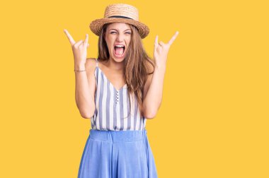 Genç, sarışın, yaz şapkası takan çılgın bir ifadeyle bağıran ve elleri havada rock sembolü yapan güzel bir kadın. Müzik yıldızı. ağır müzik konsepti. 