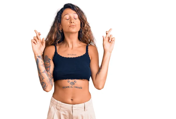 Молода Іспаномовна Жінка Татуюванням Повсякденному Одязі Жестикулює Палець Схрещеним Посміхаючись — стокове фото