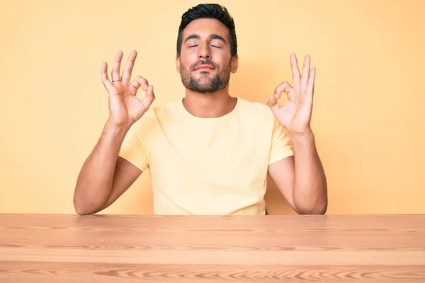 Ung Latinamerikan Man Bär Casual Kläder Sitter Bordet Slappna Och — Stockfoto