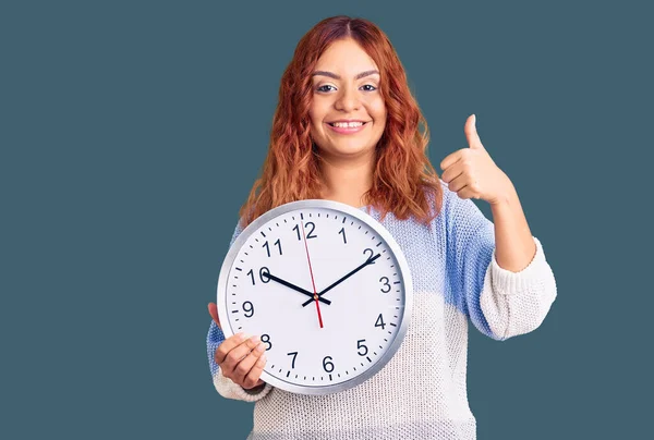 Mujer Latina Joven Sosteniendo Gran Reloj Sonriendo Feliz Positivo Pulgar — Foto de Stock