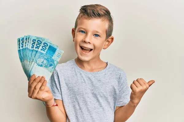 Urocze Kaukaskie Dziecko Trzymające 100 Brazylijskich Banknotów Skierowanych Kciukiem Górę — Zdjęcie stockowe