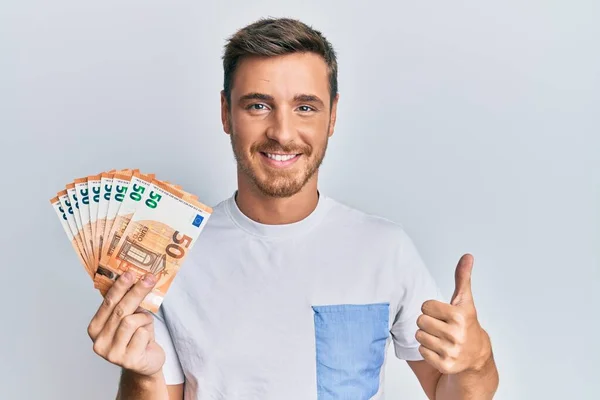 Hombre Caucásico Guapo Sosteniendo Billetes Euros Sonriendo Feliz Positivo Pulgar —  Fotos de Stock