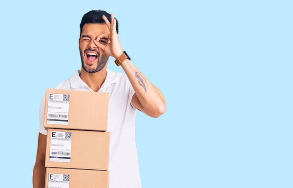 Homem Hispânico Bonito Jovem Segurando Pacote Entrega Sorrindo Feliz Fazendo — Fotografia de Stock