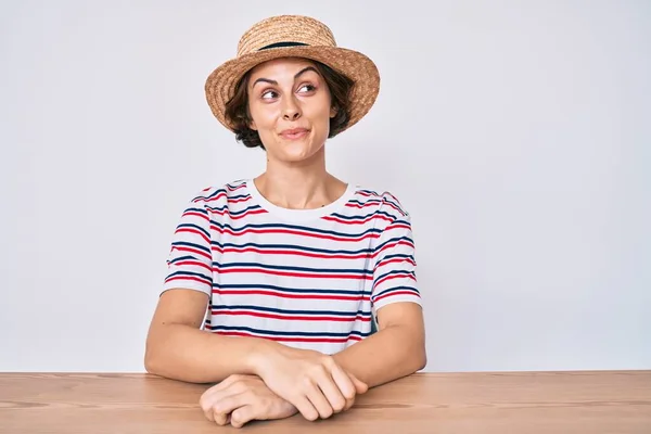 Mladá Hispánka Neformálním Oblečení Klobouku Sedí Stole Usmívá Dívá Stranou — Stock fotografie
