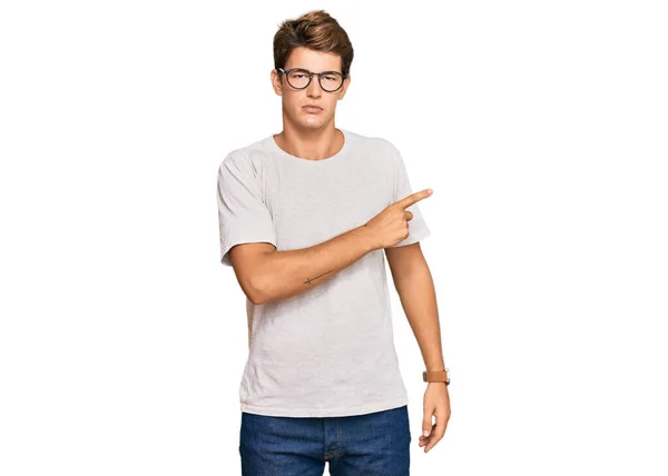 Hezký Běloch Neformálním Oblečení Brýlích Ukazující Ukazováčkem Stranu Reklamou Vážnou — Stock fotografie