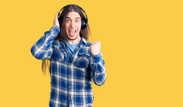 Uzun Saçlı Müzik Dinleyen Kulaklıklı Genç Bir Adam Gururla Bağırıyor — Stok fotoğraf