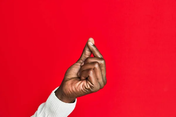 Arm and hand of african american black young man over red isolated background holding blank space with thumb finger, business and advertising