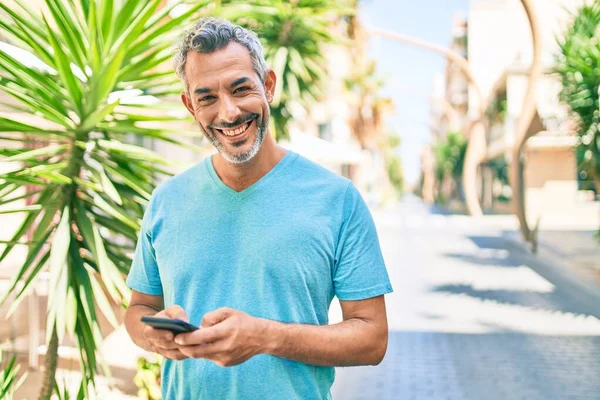 Středního Věku Šedovlasý Muž Úsměvem Šťastný Pomocí Smartphone Chůze Ulici — Stock fotografie