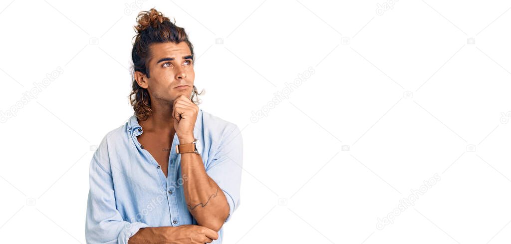 Young hispanic man wearing summer style with hand on chin thinking about question, pensive expression. smiling with thoughtful face. doubt concept. 