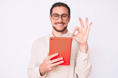 Genç yakışıklı adam dokunmatik ped kullanıyor. Parmaklarıyla imza atıyor, gülümsüyor. Mükemmel bir sembol. 