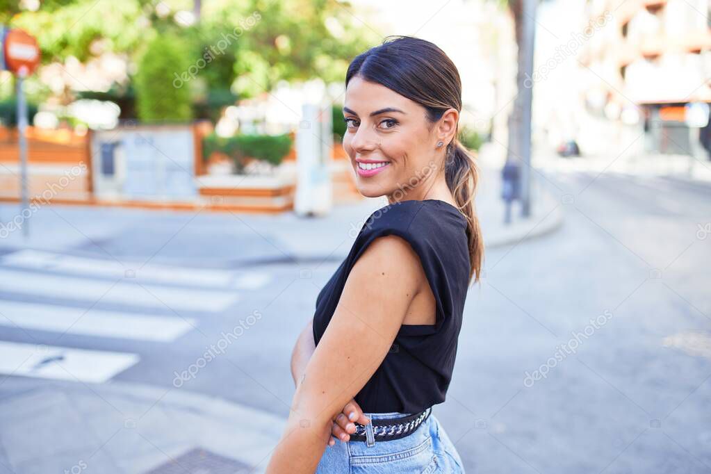 Beautiful young woman wearing fashionable clothes standing in the middle of the street at the town