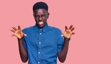 Genç Afro-Amerikan adam günlük kıyafetler giymiş komik gülüyor kedi gibi pençe hareketi yapıyor, agresif ve seksi bir ifade. 