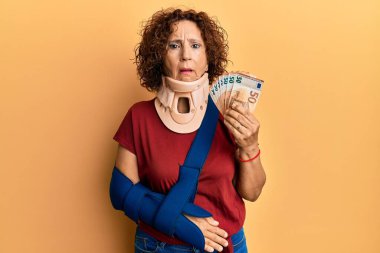 Güzel, orta yaşlı, boyun tasması takan, elinde şokla avro tutan, şüpheci ve iğneleyici bakışları olan, ağzı açık bir şekilde şaşırmış bir kadın. 