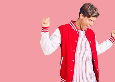 Genç yakışıklı adam beyzbol forması giyiyor mutlu ve neşeli dans ediyor, gülümsüyor rahat ve kendinden emin bir şekilde müzik dinliyor. 