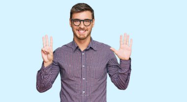 Yakışıklı beyaz adam, günlük kıyafetler ve gözlük takıyor. Sekiz numarayı gösteriyor ve işaret ediyor. Kendinden emin ve mutlu gülümsüyor.. 