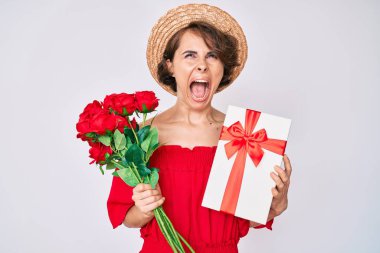 Genç İspanyol kadın yıldönümümüz için elinde bir buket çiçek ve hediye tutuyor kızgın ve öfkeli çığlıklar atıyor öfkeyle bağırıyor, öfkeyle yukarı bakıyor. 