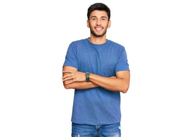 Sıradan kıyafetler giyen, kollarını kavuşturup kameraya bakan mutlu yüzlü genç bir adam. pozitif kişi. 