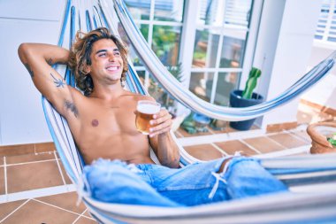 Genç İspanyol adam terasta hamakta uzanmış bira içerek rahatladı..