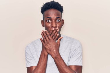 Gündelik giysiler giyen genç Afro-Amerikan bir adam yanlışlıkla elleri ile ağzını kapatırken şok oldu. gizli kavram. 