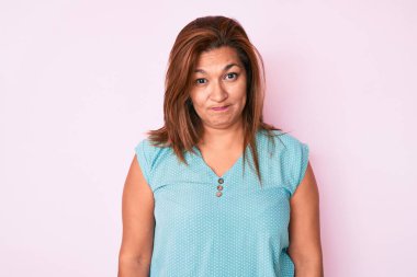 Orta yaşlı esmer, sıradan kıyafetler giyen, kuşkucu ve gergin bir kadın, sorun yüzünden surat asıyor. negatif kişi. 