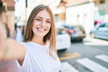 Genç beyaz kadın gülümsüyor. Şehrin kamerasının önünde selfie çekerken mutlu.