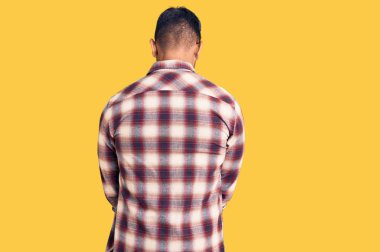 Gündelik giysiler ve gözlük takan İspanyol genç adam kollarını kavuşturup arkasını kollarını çeviriyor. 