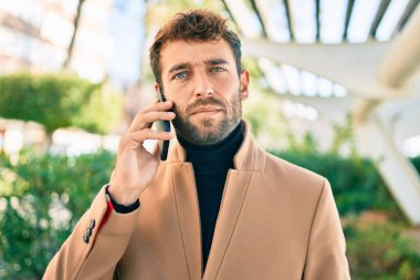 Zarif ceketli yakışıklı bir iş adamı. Açık havada akıllı telefon kullanıyor.