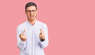 Handsome young man with bear wearing elegant business shirt and glasses showing middle finger doing fuck you bad expression, provocation and rude attitude. screaming excited 