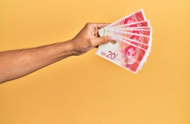 İsrail 'i tutan İspanyol' un eli. 20 şekel banknot, izole edilmiş sarı arka plan..