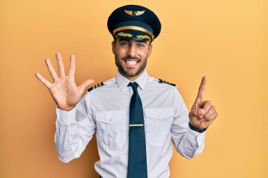Yakışıklı İspanyol pilot üniforması giyen altı numaralı parmaklarıyla kendini beğenmiş ve mutlu gülümserken.. 