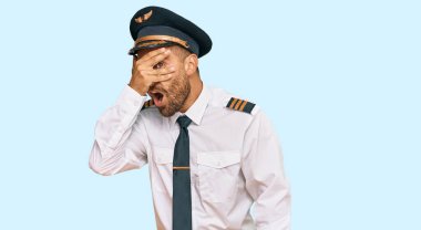 Sakallı yakışıklı bir adam, uçak pilotu üniforması giyiyor. Şok geçiriyor, yüzünü ve gözlerini eliyle kapatıyor, utangaç ifadesiyle parmaklarından bakıyor.. 