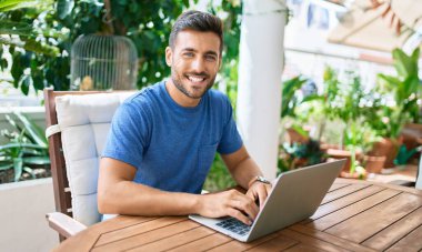 Terasta dizüstü bilgisayar kullanan genç bir İspanyol..