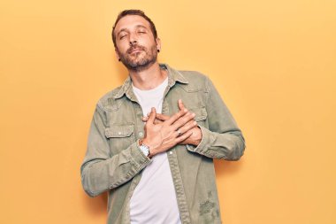 Sıradan kıyafetler giyen, elleri göğsünde, gözleri kapalı gülümseyen ve yüzünde minnet ifadesi olan genç yakışıklı bir adam. sağlık kavramı. 