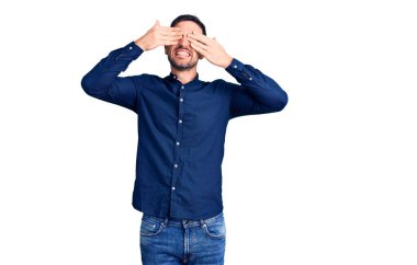 Genç ve yakışıklı bir adam, günlük gömlekler giyip, gözlerini kapayıp, neşeli ve komik gülümsüyor. kör kavram. 