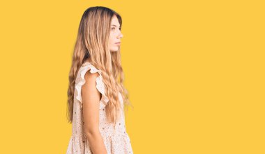 Sarışın, güzel, beyaz bir kadın. Zarif yaz kıyafetleri giyiyor. Yan tarafa bakıyor.. 