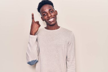 Genç Afrikalı Amerikalı sıradan kıyafetler giyen bir fikir veya soruyla gülümseyen mutlu bir yüzle işaret eden bir adam. 