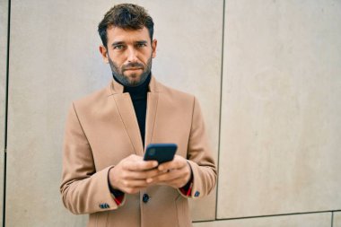 Zarif ceketli yakışıklı bir iş adamı. Açık havada akıllı telefon kullanıyor.