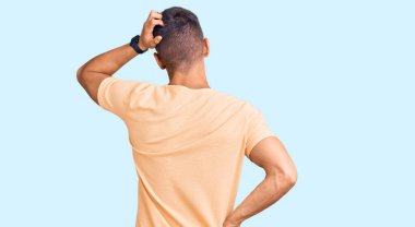 Genç ve yakışıklı bir adam günlük kıyafetlerini ters giyip elleri kafasında şüpheyi düşünüyor. 