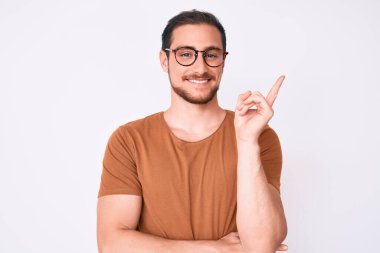 Gündelik kıyafetler ve gözlük takan genç yakışıklı adam gülümsüyor mutlu bir şekilde elini ve parmağını yana uzatıyordu. 