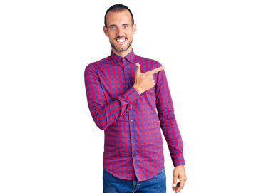 Genç, yakışıklı, günlük kıyafetler giyen, neşeli, yüzünde mutlu ve doğal bir ifadeyle, elleri ve parmaklarıyla işaret eden bir gülümseme olan bir adam. 