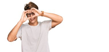 Yakışıklı beyaz adam, günlük kıyafetler ve gözlük takıyor kalp şeklinde el ve parmaklarıyla tabelalardan bakıp gülümsüyor. 