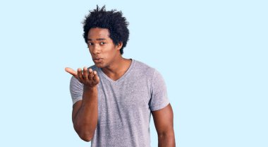 Yakışıklı, Afro saçlı, sıradan kıyafetler giyen ve havada el ele öpüşerek güzel ve seksi bir şekilde kameraya bakan Afro-Amerikan erkeği. aşk ifadesi. 