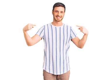 Ayılı yakışıklı genç adam gündelik kıyafetler giyiyor. Kendine güvenen, gülümseyen, kendini gururlu ve mutlu bir şekilde gösteren.. 