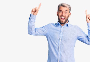 Zarif bir tişört giyen yakışıklı genç adam şaşırmış, şaşırmış ve parmaklarıyla işaret ediyor ve kollarını kaldırıyordu.. 